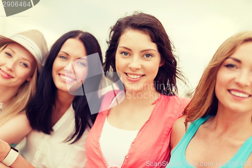 Image of group of smiling girls chilling on the beach