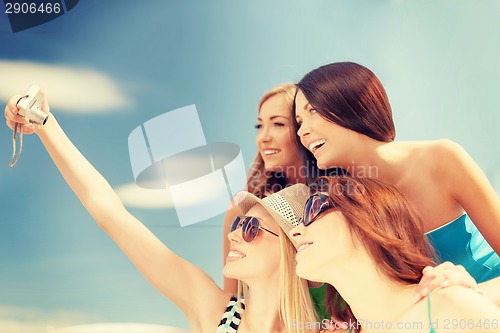 Image of smiling girls taking photo in cafe on the beach