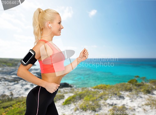 Image of sporty woman running with smartphone and earphones