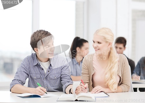 Image of two teenagers with notebooks and book at school