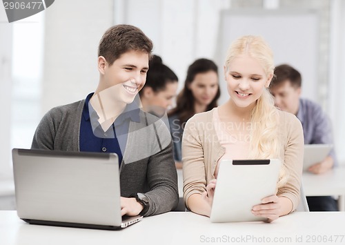 Image of two smiling students with laptop and tablet pc