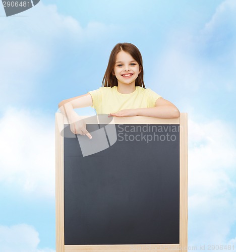 Image of happy little girl pointing finger to blackboard