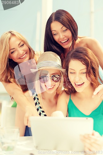 Image of smiling girls looking at tablet pc in cafe