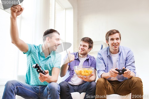 Image of smiling friends playing video games at home