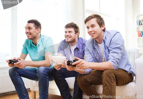 Image of smiling friends playing video games at home