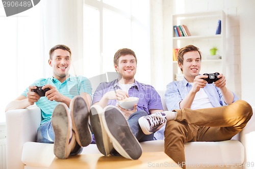 Image of smiling friends playing video games at home