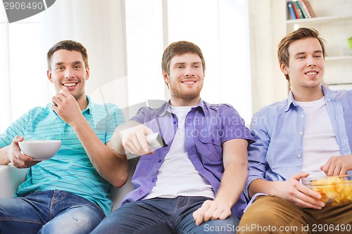 Image of happy male friends watching tv at home