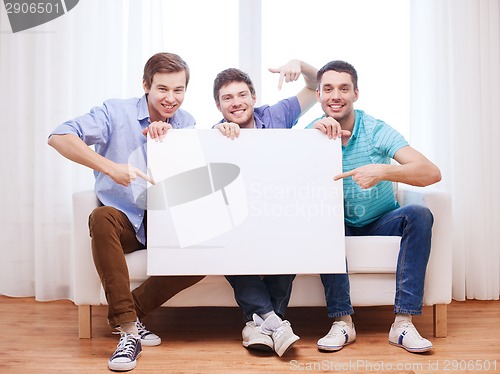 Image of happy male friends with blank white board at home