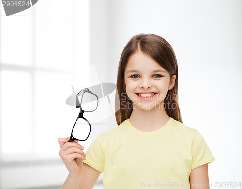 Image of smiling cute little girl holding black eyeglasses