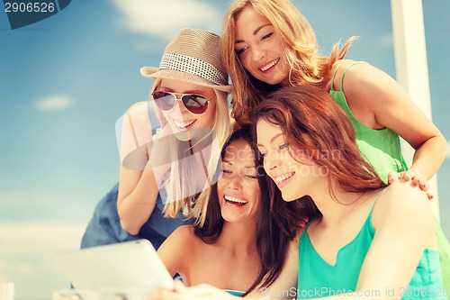 Image of smiling girls looking at tablet pc in cafe