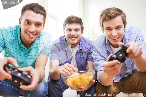 Image of smiling friends playing video games at home