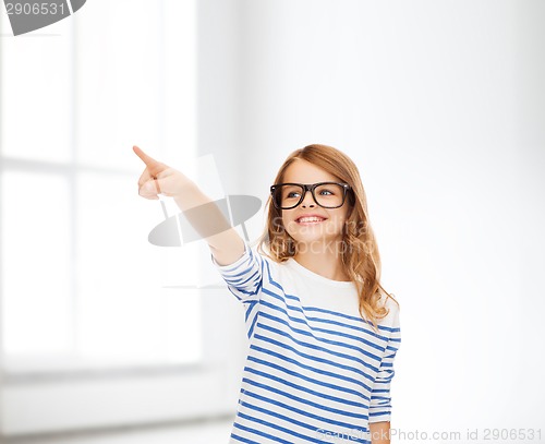 Image of cute little girl in eyeglasses pointing in the air