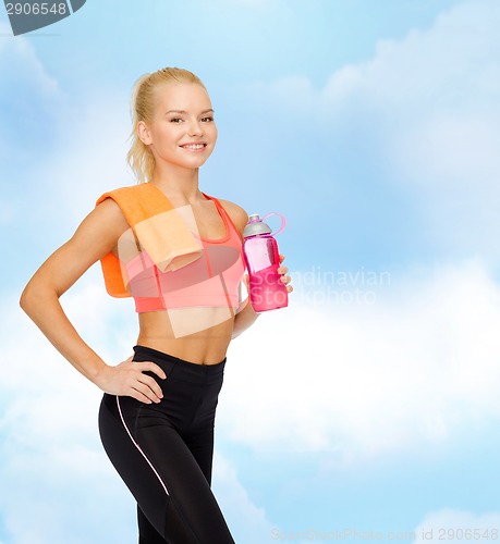 Image of smiling sporty woman with water bottle and towel