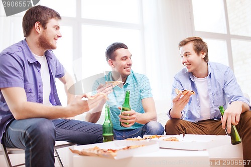 Image of five smiling teenagers eating pizza at home