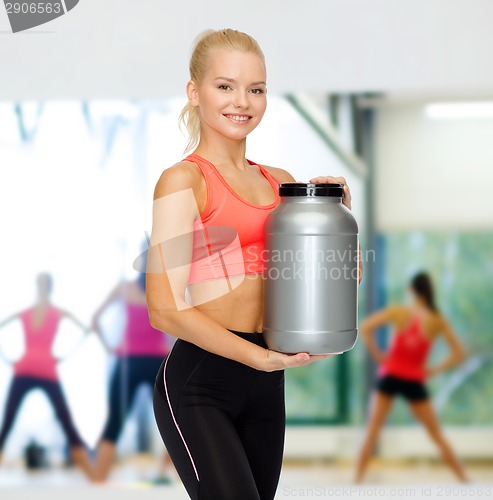 Image of smiling sporty woman with jar of protein