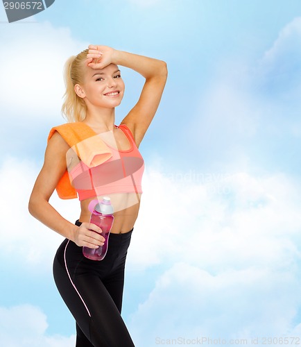 Image of smiling sporty woman with towel and water bottle