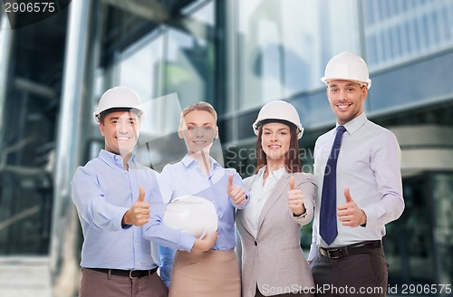 Image of happy business team in office showing thumbs up