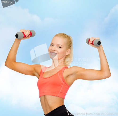 Image of smiling beautiful sporty woman with dumbbells