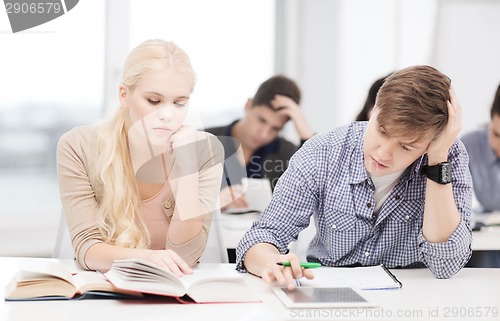 Image of tired students with tablet pc, books and notebooks
