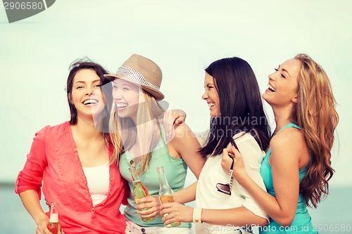 Image of smiling girls with drinks on the beach