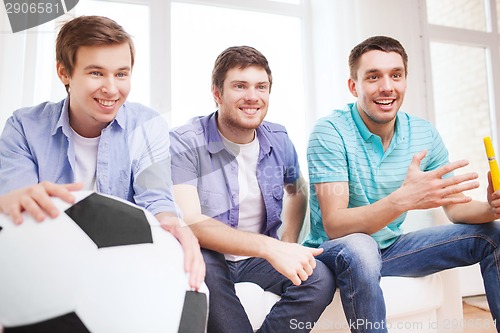 Image of happy male friends with vuvuzela