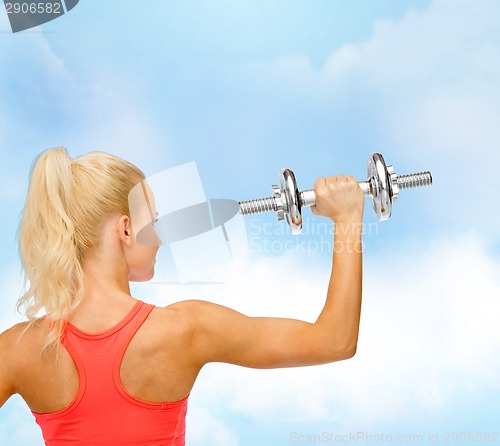 Image of sporty woman with heavy steel dumbbell from back