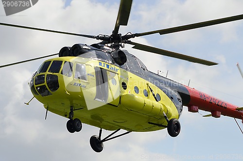 Image of The yellow MI-8 helicopter flies against clouds with an open doo
