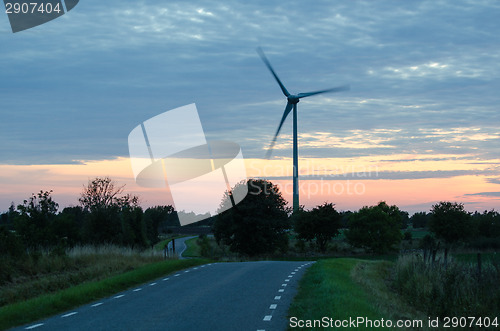 Image of Wind turbine by a winding road at late evening