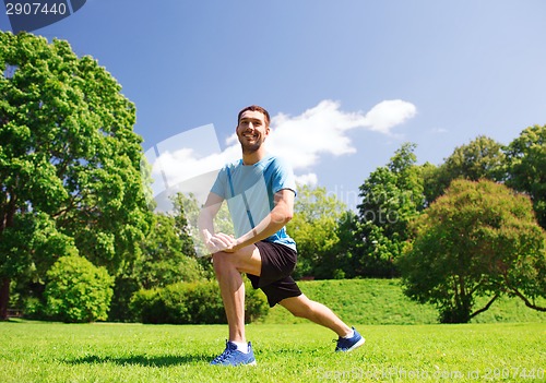 Image of smiling man stretching outdoors