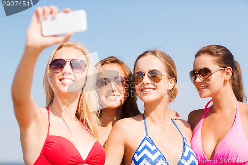 Image of group of smiling women making selfie on beach