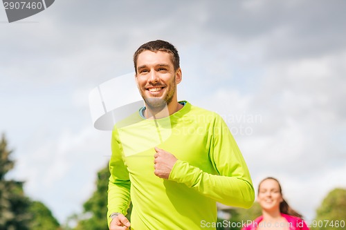 Image of smiling couple running outdoors