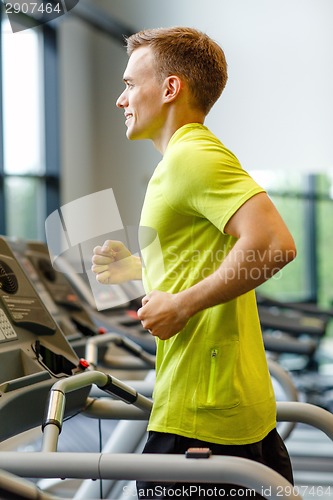 Image of smiling man exercising on treadmill in gym