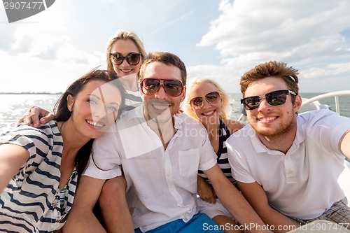 Image of smiling friends sitting on yacht deck