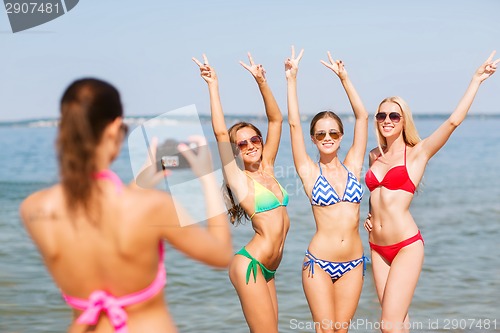 Image of group of smiling women photographing on beach