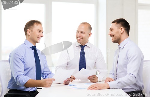 Image of smiling businessmen with papers in office