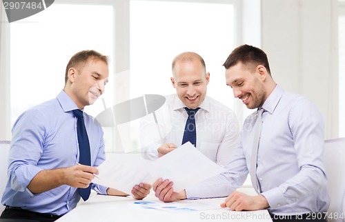 Image of smiling businessmen with papers in office