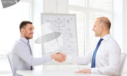 Image of two smiling businessmen shaking hands in office