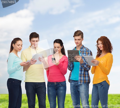 Image of group of teenagers with smartphones and tablet pc