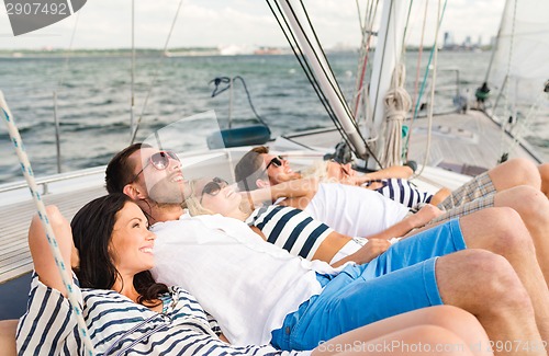 Image of smiling friends lying on yacht deck