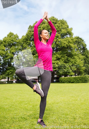 Image of smiling african american woman exercising outdoors