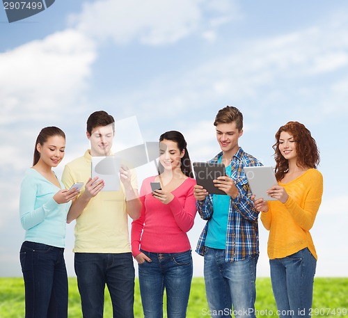 Image of group of teenagers with smartphones and tablet pc