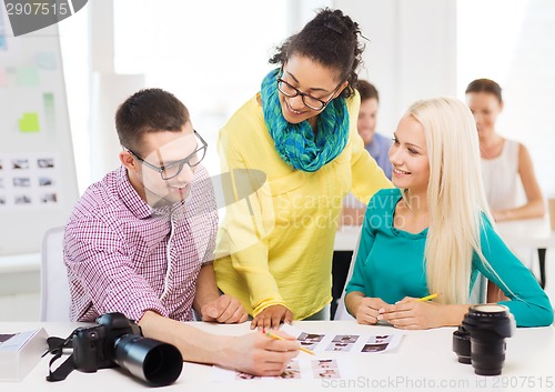 Image of smiling team with printed photos working in office