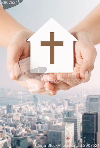 Image of close up of hands and paper house with cross