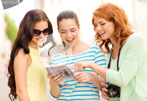 Image of smiling teenage girls with city guide and camera