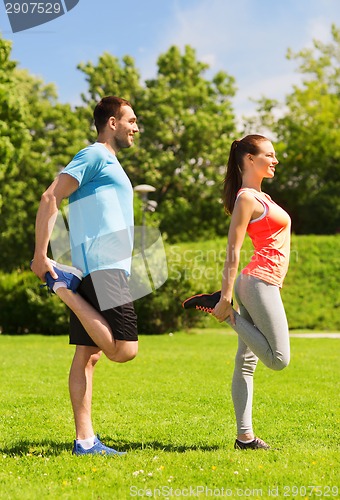 Image of smiling couple stretching outdoors