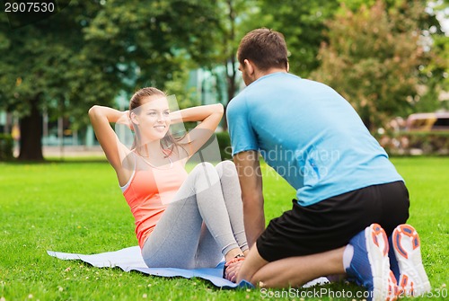 Image of smiling woman doing exercises on mat outdoors