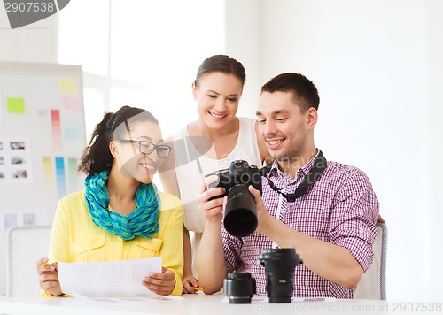 Image of smiling team with photocamera working in office