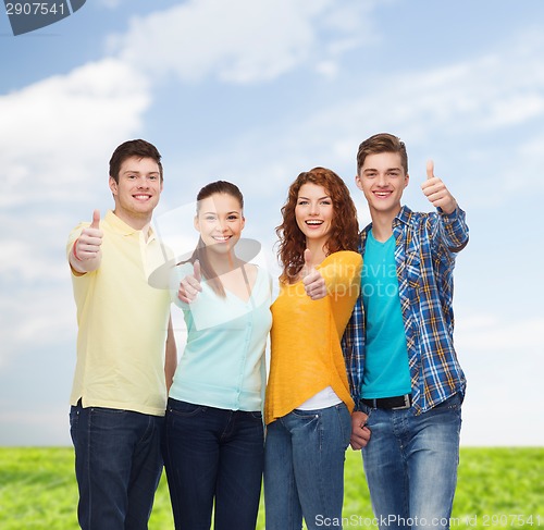 Image of group of smiling teenagers over blue sky and grass