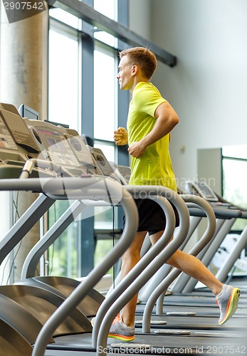 Image of smiling man exercising on treadmill in gym