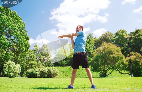 Image of smiling man stretching outdoors